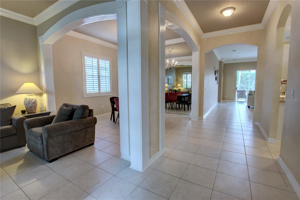 A tiled hallway leads past arched architectural columns into a living area and dining room — 1467 CHESSINGTON CIRCLE, LAKE MARY, FL