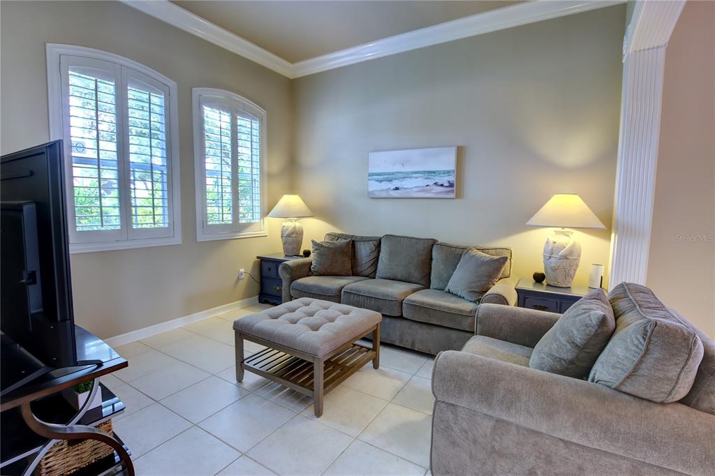 A living room features a gray sofa, matching armchair, tufted ottoman, and two table lamps — 1467 CHESSINGTON CIRCLE, LAKE MARY, FL