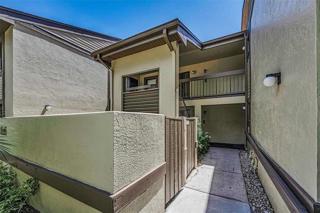 A concrete walkway leads to a gated entrance and a two-story building exterior — 124 WOODLAKE WYNDE UNIT 0, OLDSMAR, FL