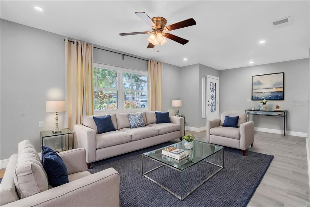 A living room features a beige sofa, two armchairs, a glass coffee table, and a rug — 5619 DENVER STREET NE, ST PETERSBURG, FL