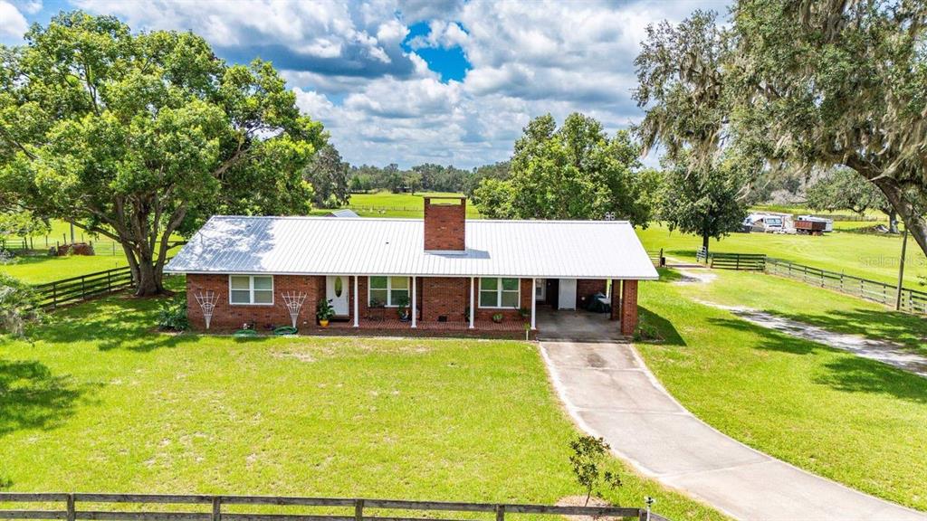 A single-story brick house with a white metal roof and a concrete driveway — 38730 MICKLER ROAD, DADE CITY, FL