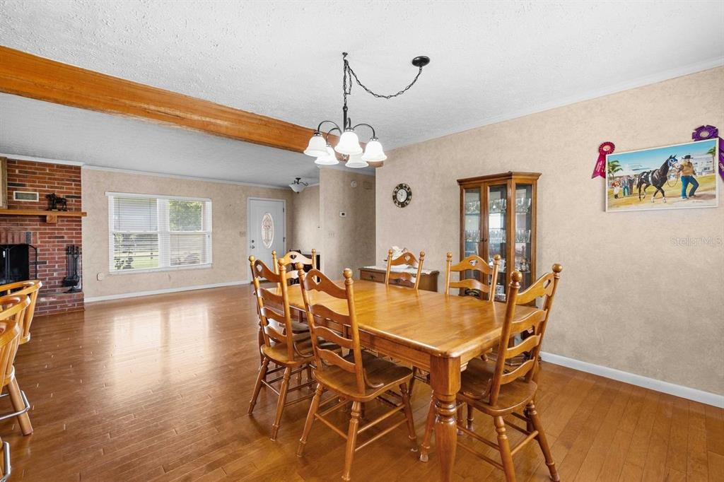 A dining room features a wooden table, chairs, a brick fireplace, and hardwood flooring — 38730 MICKLER ROAD, DADE CITY, FL