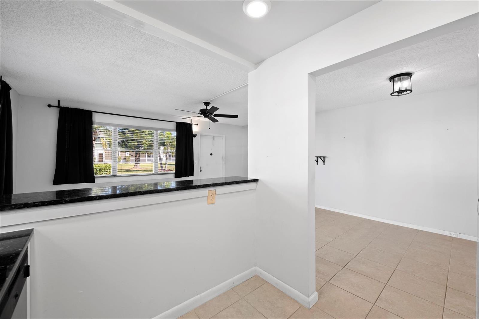 A kitchen with a black granite breakfast bar overlooks a living area with tile flooring — 28 Prescott B # 28, Deerfield Beach FL 33442, DEERFIELD BEACH, FL