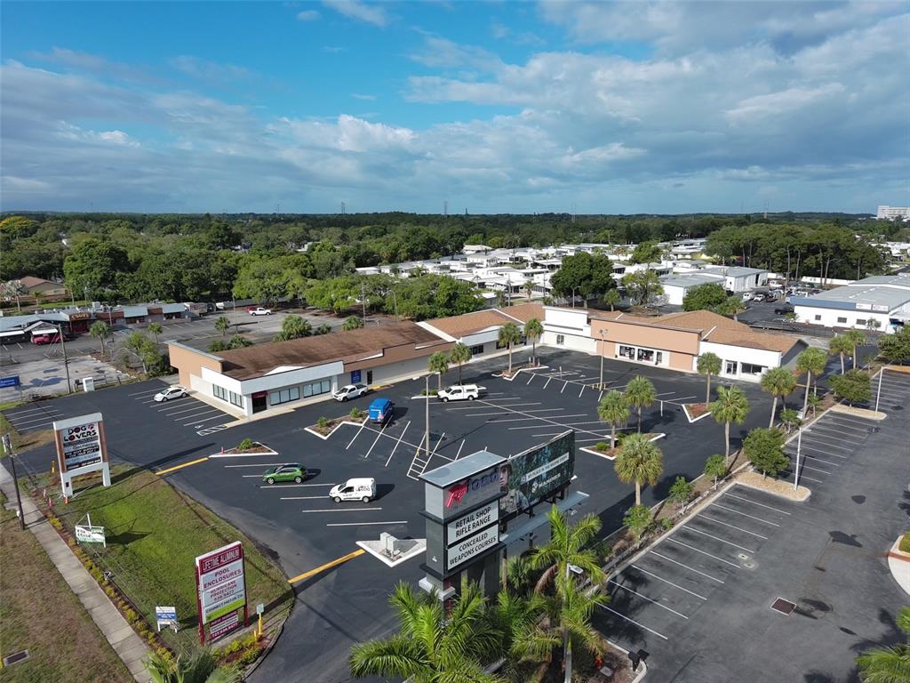 An aerial view shows a commercial strip mall with a large parking lot and signage — 39930 US HIGHWAY 19 N, TARPON SPRINGS, FL
