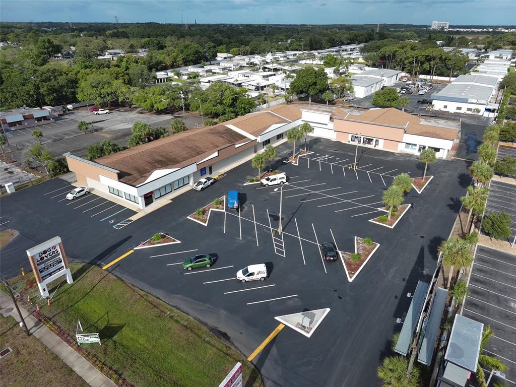 An aerial view shows a commercial building with a large parking lot and surrounding trees — 39930 US HIGHWAY 19 N, TARPON SPRINGS, FL