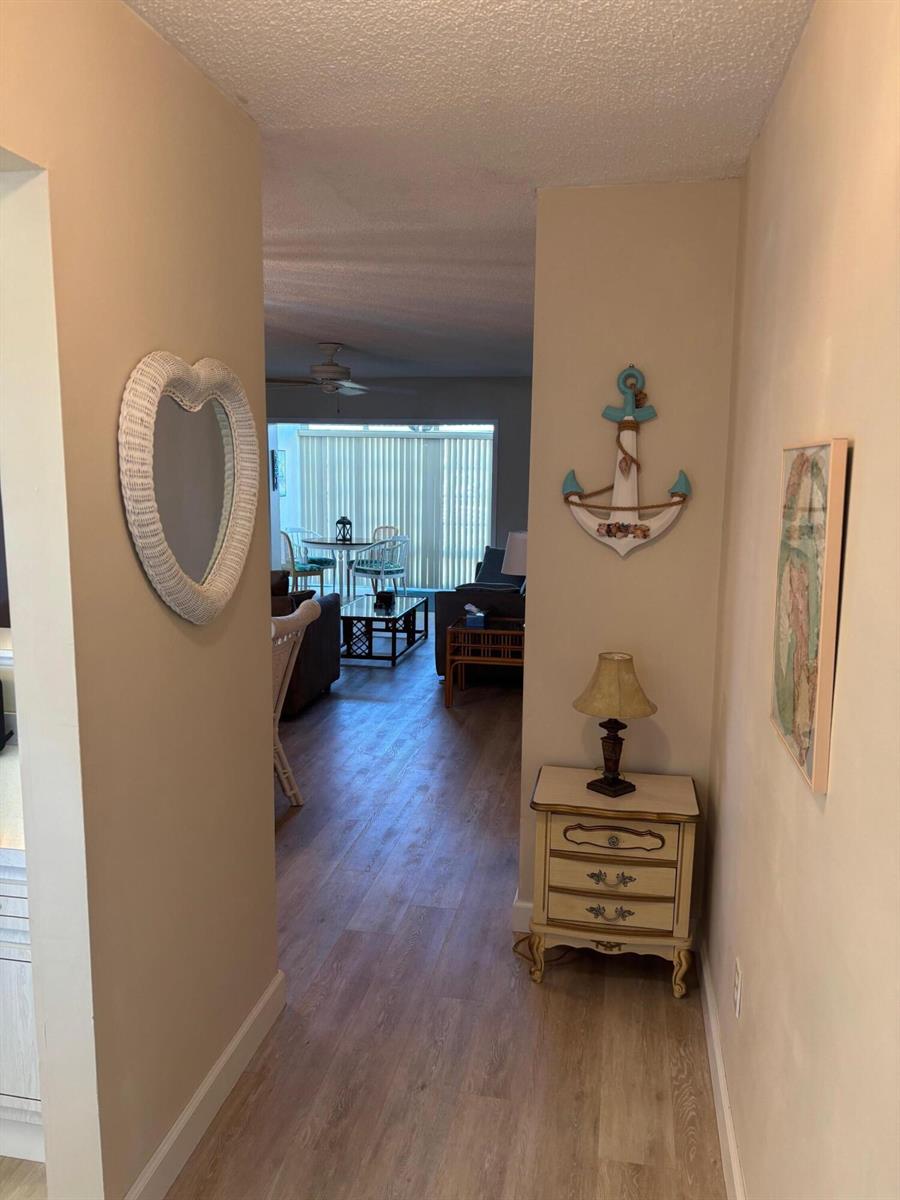 A hallway with light wood flooring leads into a living area with a dining set — 2950 SE Ocean Boulevard # 5, Stuart FL 34996, STUART, FL