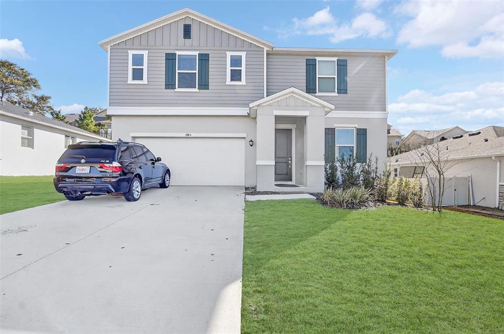 A two-story suburban house with a gray exterior, a two-car garage, and a driveway — 1985 BURGUNDY DRIVE, MINNEOLA, FL