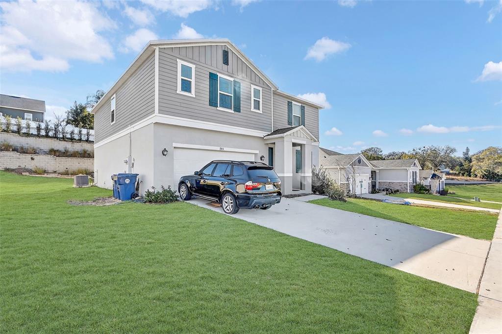 A two-story house with gray siding and a concrete driveway features a parked SUV — 1985 BURGUNDY DRIVE, MINNEOLA, FL
