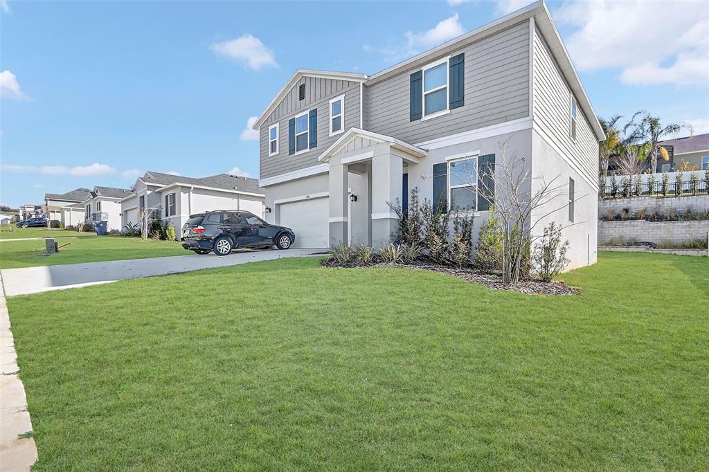 A two-story suburban house features a gray exterior, a front lawn, and a driveway — 1985 BURGUNDY DRIVE, MINNEOLA, FL