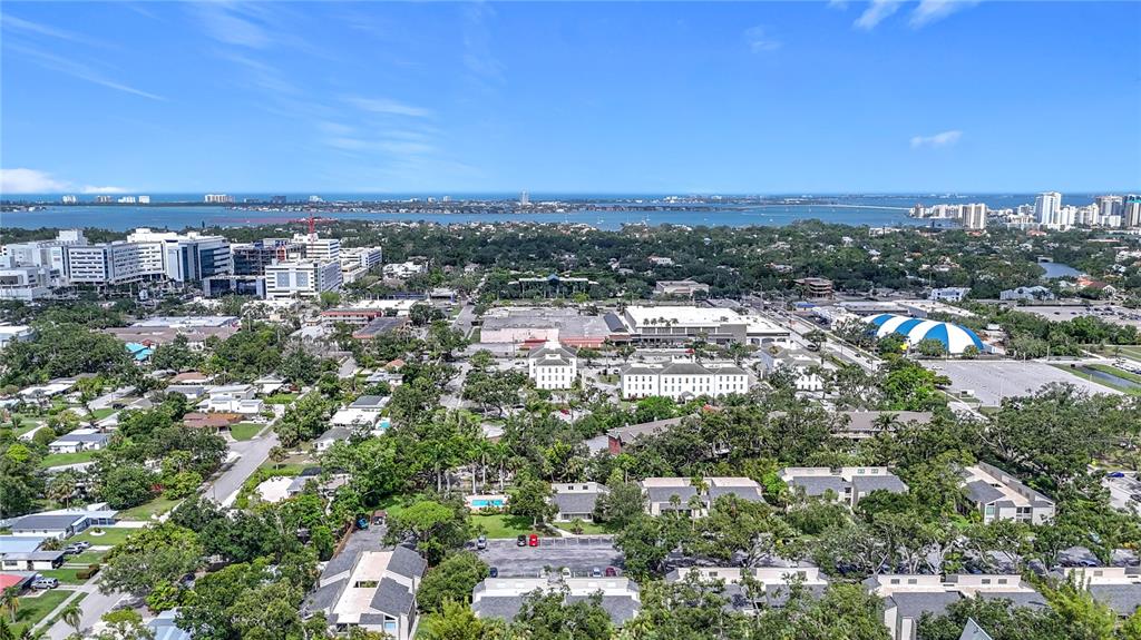 An aerial view shows a suburban neighborhood with trees, buildings, and a distant bay — 2220 BAHIA VISTA STREET UNIT G5, SARASOTA, FL