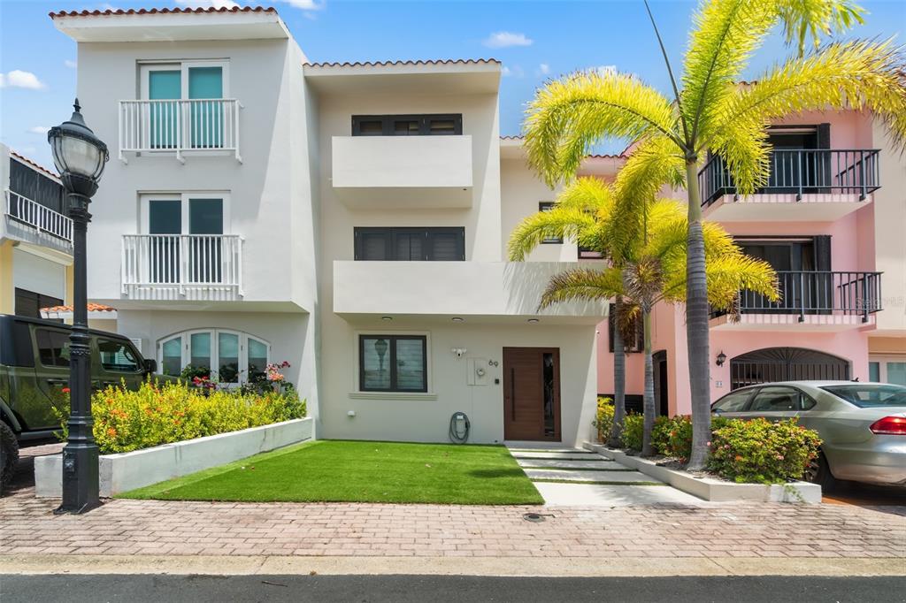 A three-story white townhouse with a front lawn, palm trees, and a paved driveway — 69 ISLA SAN MIGUEL, HUMACAO, PR