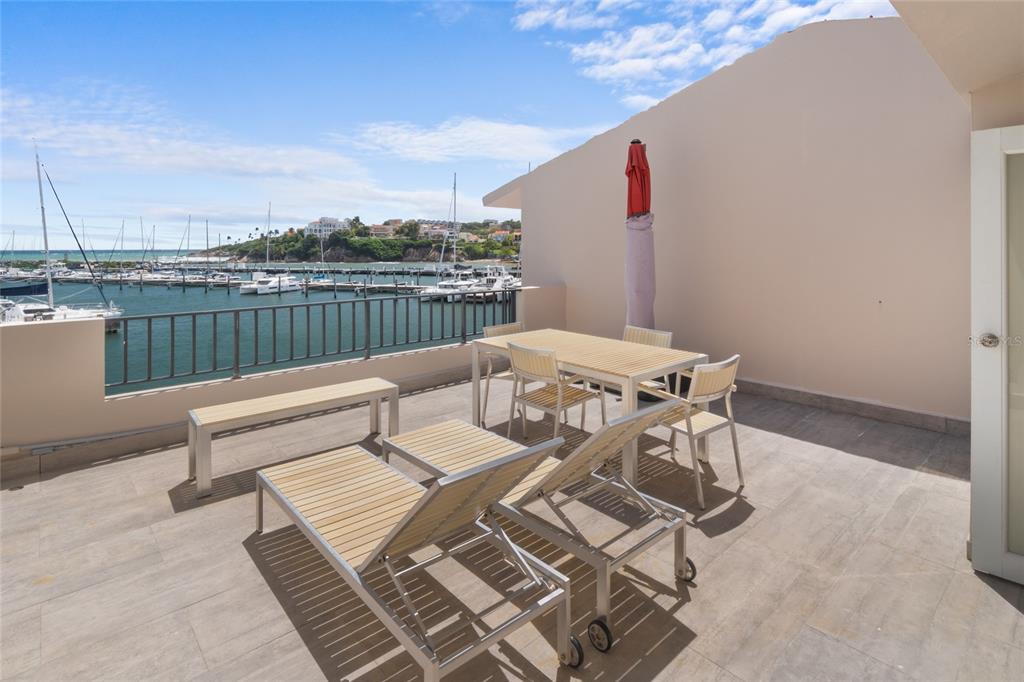 A balcony with outdoor furniture overlooks a marina with boats under a blue sky — 69 ISLA SAN MIGUEL, HUMACAO, PR