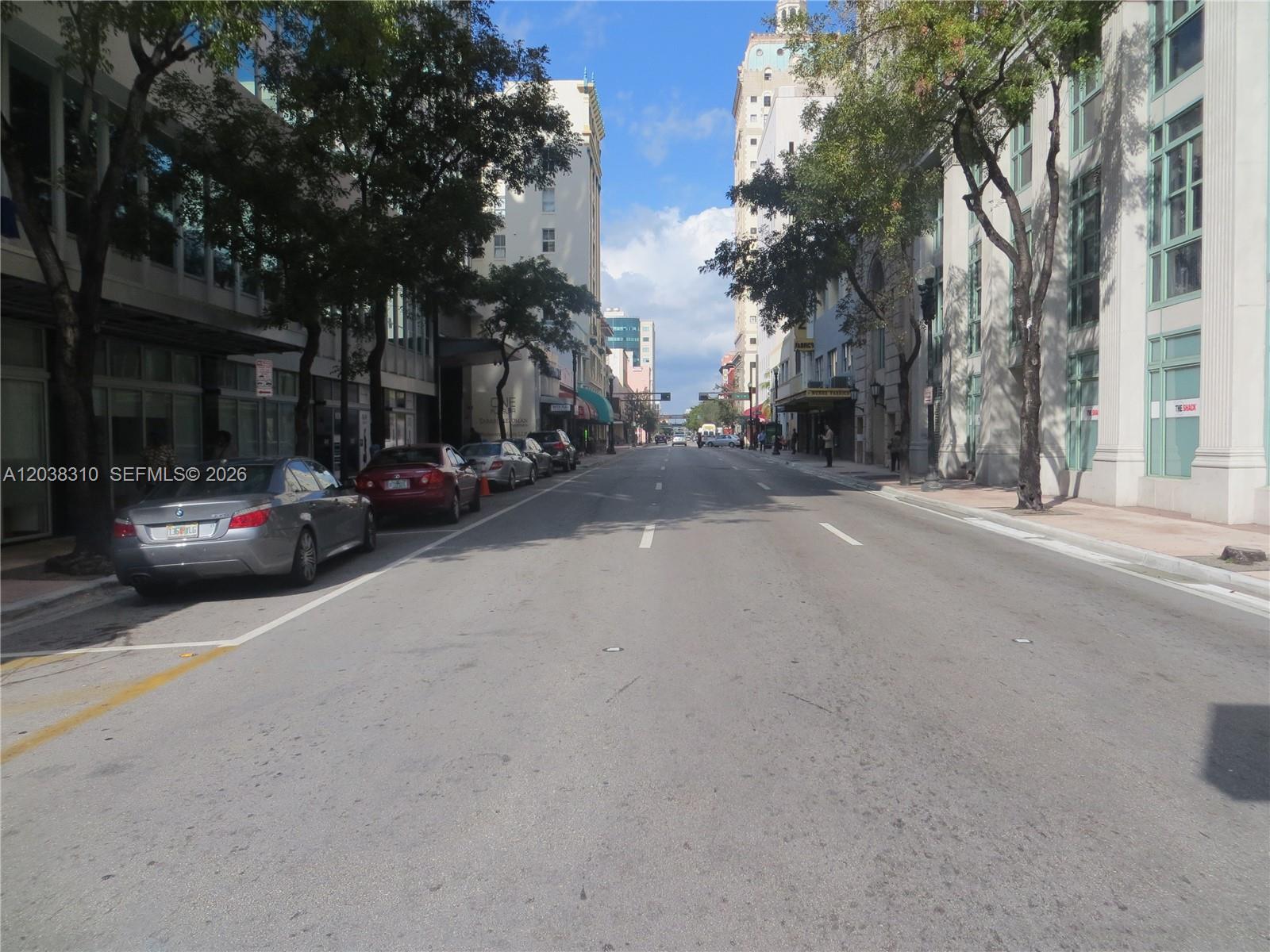A street view shows parked cars along a city road lined with buildings and trees — 111 E Flagler St # 503, Miami FL 33131, MIAMI, FL