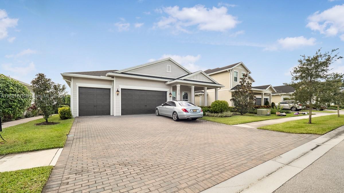 A single-story suburban house with a paved driveway, a three-car garage, and a silver sedan — 19540 Wheelbarrow Bnd, Loxahatchee FL 33470, LOXAHATCHEE, FL