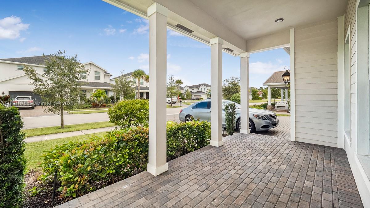 A covered brick porch features white columns and a view of a suburban street — 19540 Wheelbarrow Bnd, Loxahatchee FL 33470, LOXAHATCHEE, FL