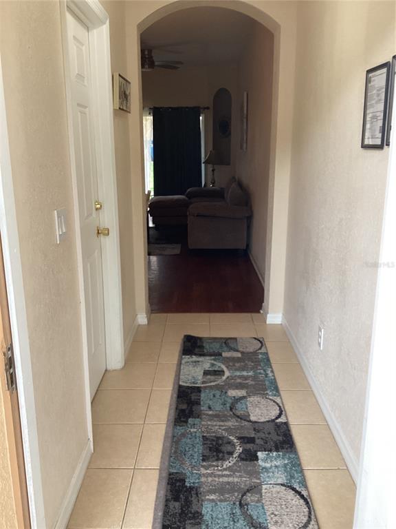 A tiled entryway leads through an arched doorway into a living area with hardwood floors — 624 TERRA LAGO STREET, DAVENPORT, FL