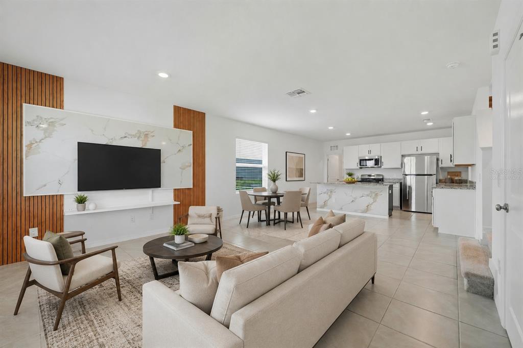 An open-concept living room and kitchen featuring a marble accent wall and tile flooring — 15056 WINDFLOWER ALLEY, WINTER GARDEN, FL