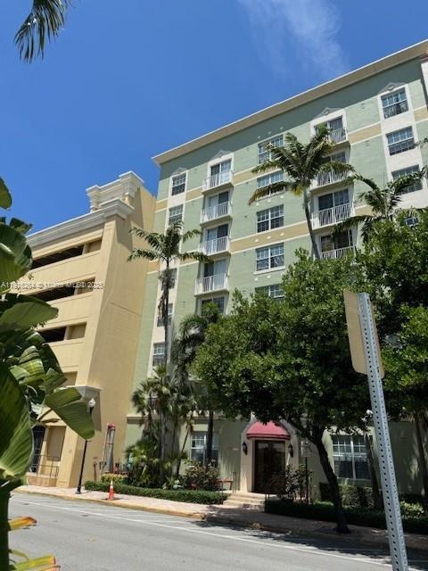 A multi-story green residential building stands next to a tan parking structure under a blue sky — 1919 Van Buren St # 516A, Hollywood FL 33020, HOLLYWOOD, FL
