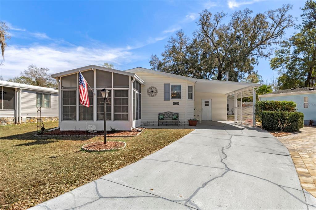 A single-story manufactured home with a screened-in porch, carport, and a cracked concrete driveway — 2805 KINGSWOOD CIRCLE, BROOKSVILLE, FL