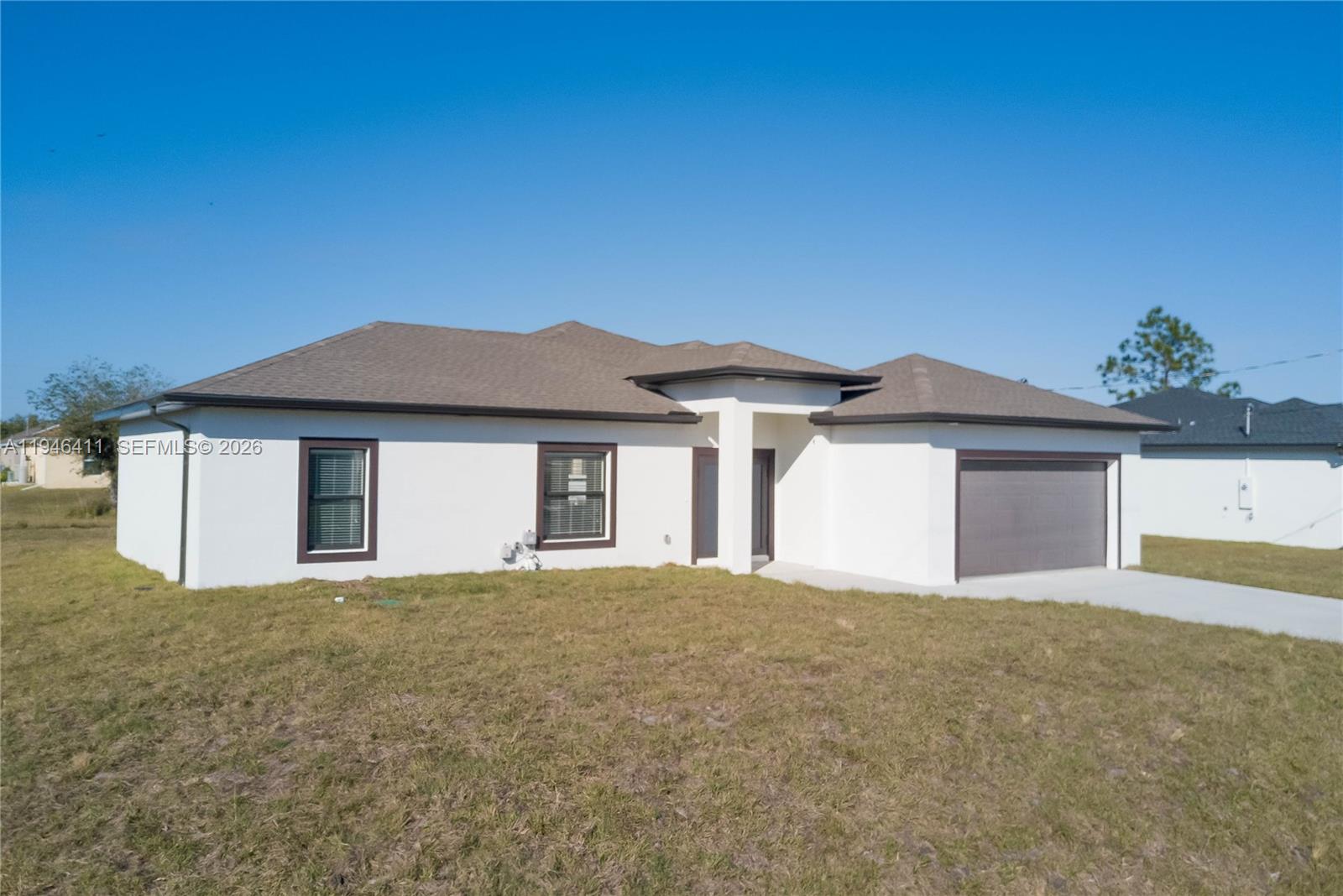 A single-story white house with a brown roof and a two-car garage — 6015 RENA AVE N, Lehigh Acres FL 33971, LEHIGH ACRES, FL