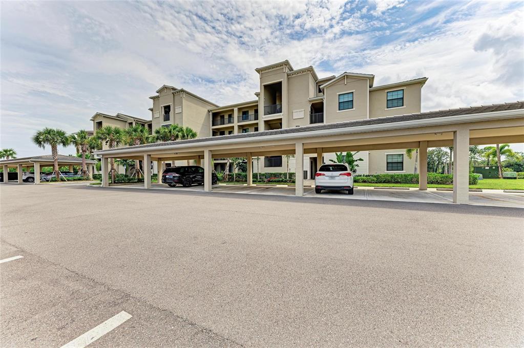 A multi-story apartment building features a large covered parking structure in the foreground — 18114 GAWTHROP DRIVE UNIT 306, BRADENTON, FL