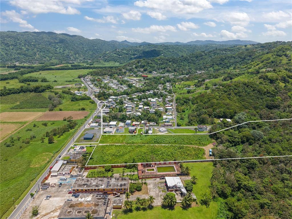 An aerial view shows a large, rectangular plot of land outlined in white near buildings — PR 182 KM 3.3 BO. CALABAZAS, YABUCOA, PR