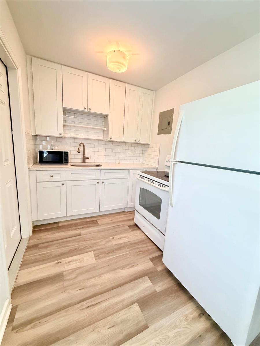A small kitchen features white cabinets, a white stove, a refrigerator, and wood-look flooring — 1502 N J Street # 2, FL 33460, FL