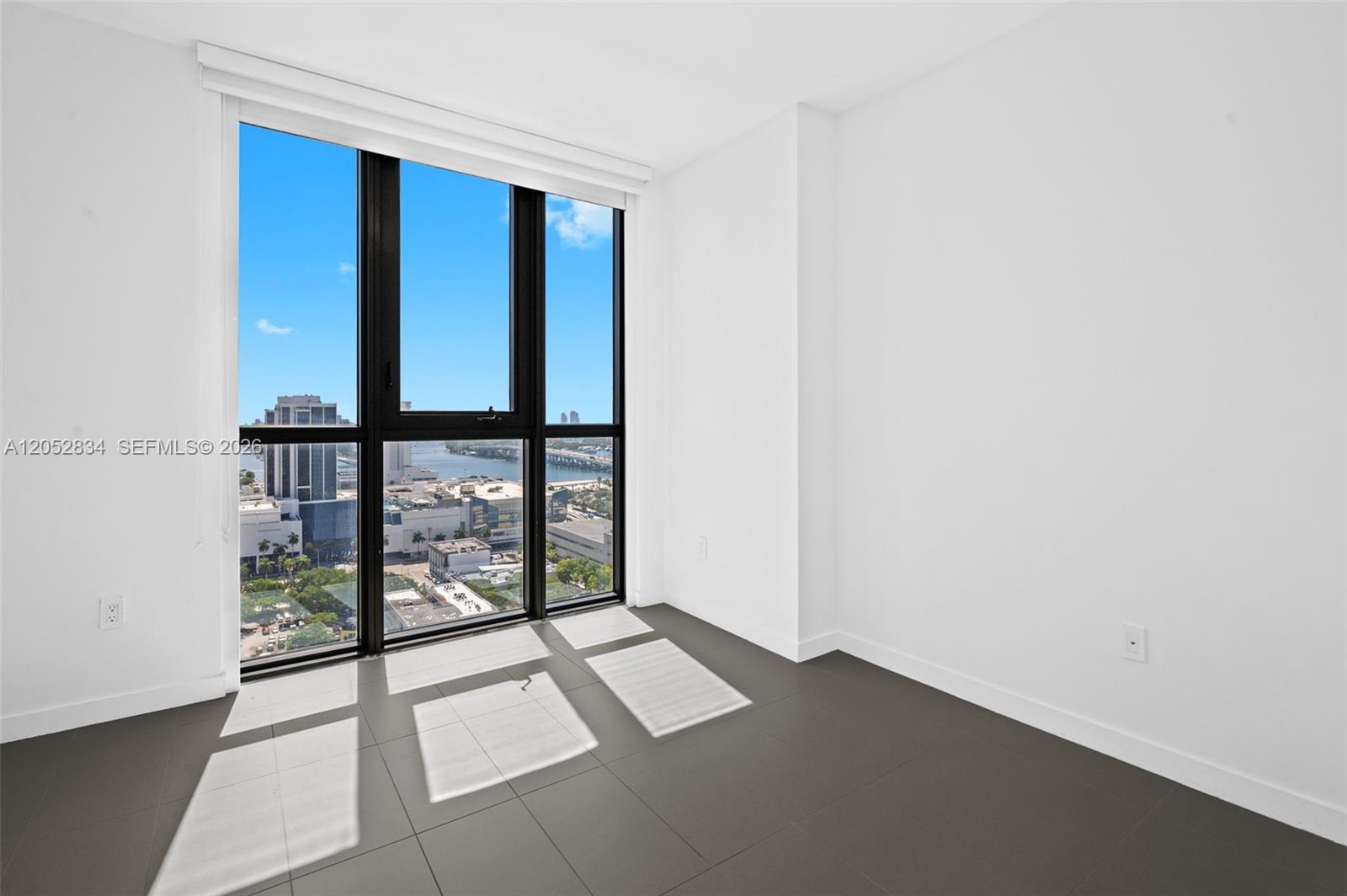 An empty room features dark tile flooring, white walls, and floor-to-ceiling windows with city views — 1600 NE 1st Ave # 2420, Miami FL 33132, MIAMI, FL