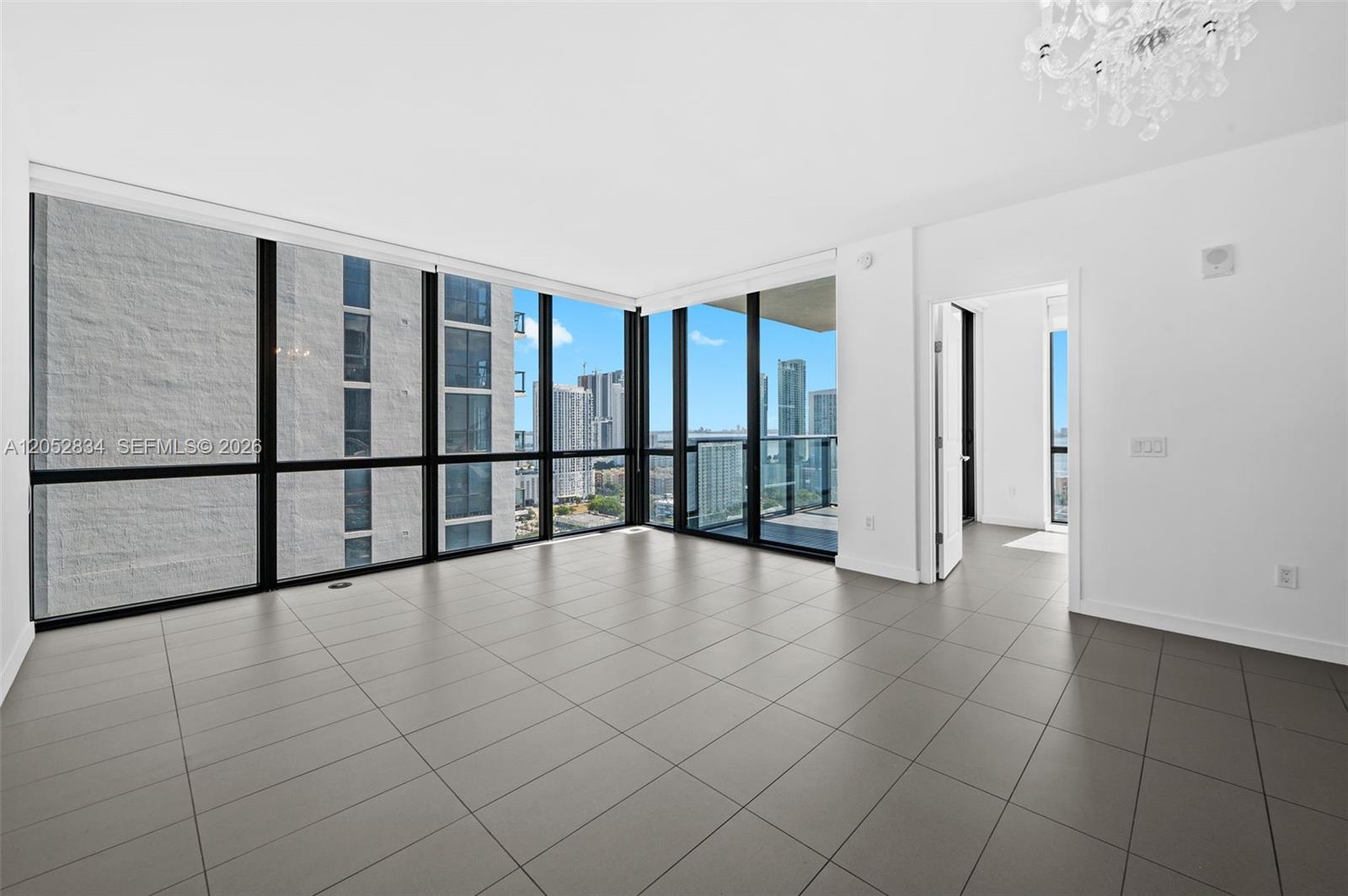 An empty room features large floor-to-ceiling windows, gray tile flooring, and a white ceiling — 1600 NE 1st Ave # 2420, Miami FL 33132, MIAMI, FL