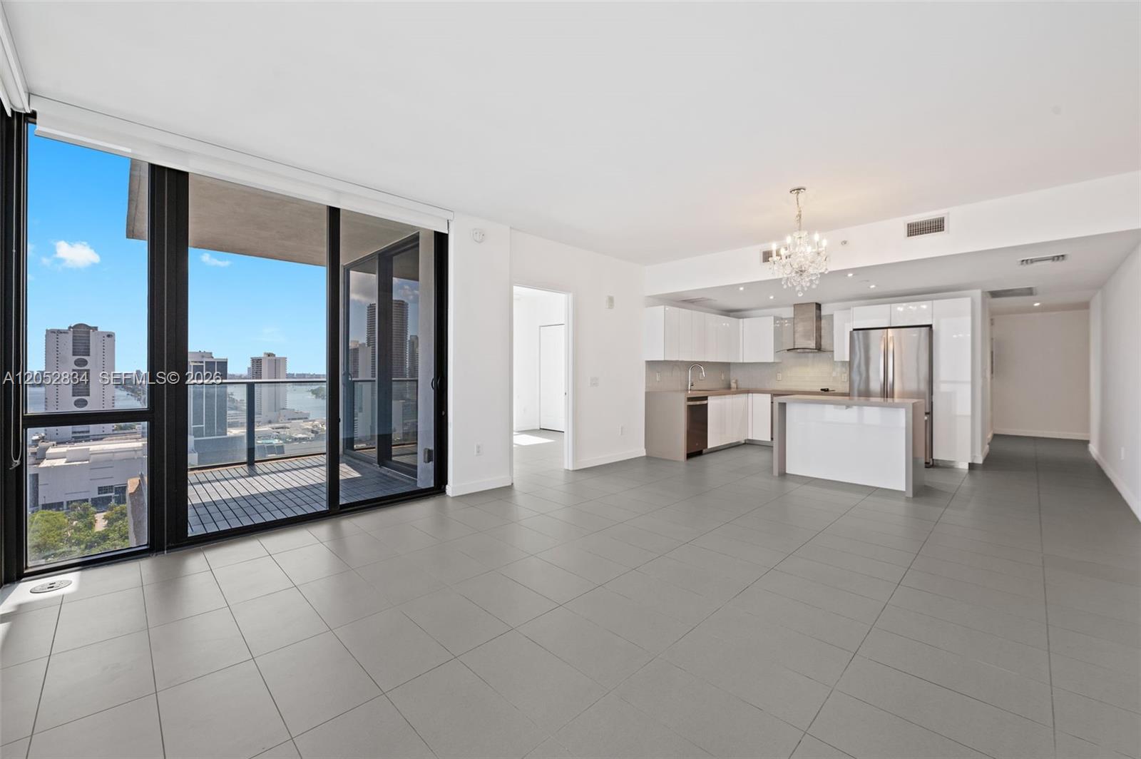 An open-concept apartment with a modern kitchen, gray tile floors, and a balcony with views — 1600 NE 1st Ave # 2420, Miami FL 33132, MIAMI, FL
