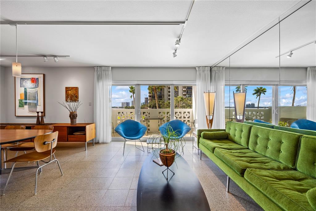 A mid-century modern living room features a green sofa, blue chairs, and a balcony view — 2401 BAYSHORE BOULEVARD UNIT 410 & 510, TAMPA, FL