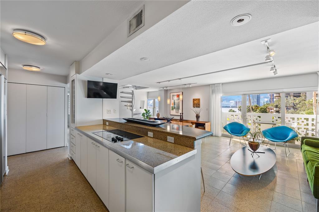 A kitchen with granite countertops overlooks a living area with blue chairs and a balcony — 2401 BAYSHORE BOULEVARD UNIT 410 & 510, TAMPA, FL