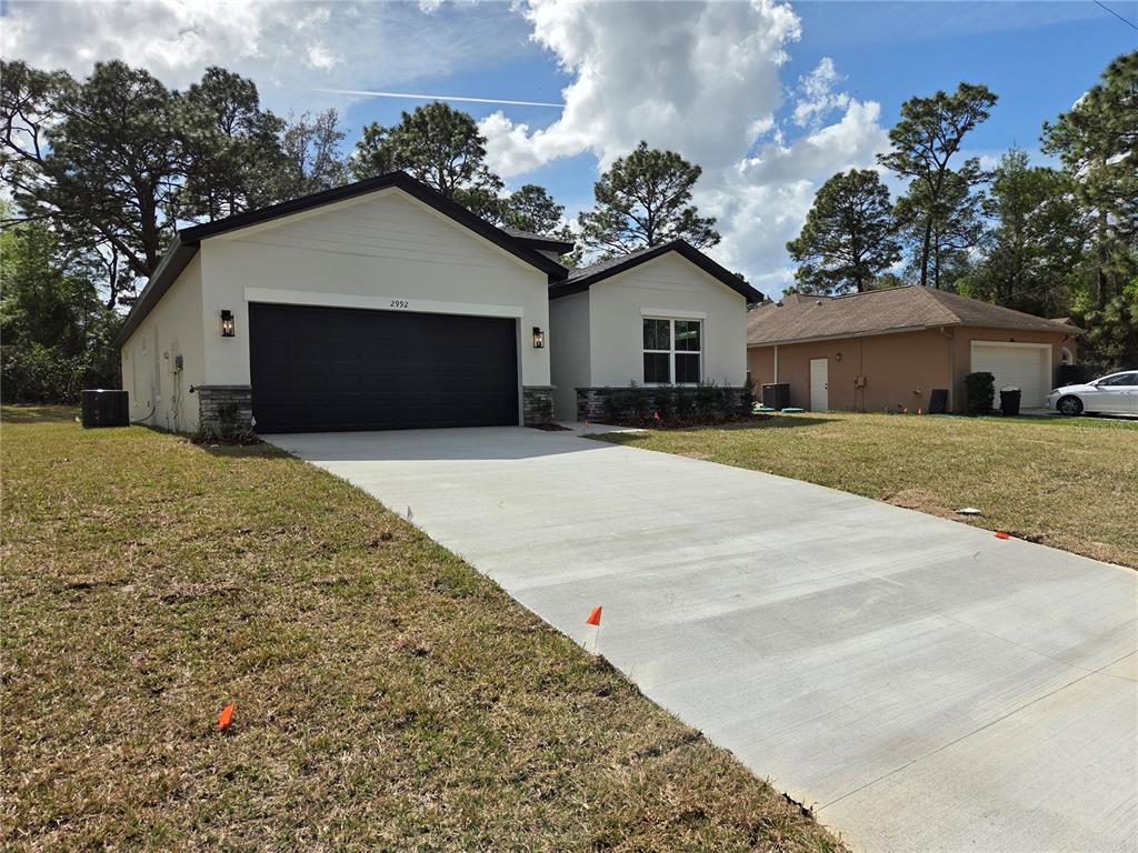 A modern single-story house with a black garage door and a concrete driveway — 2992 W HAMLET PLACE, DUNNELLON, FL