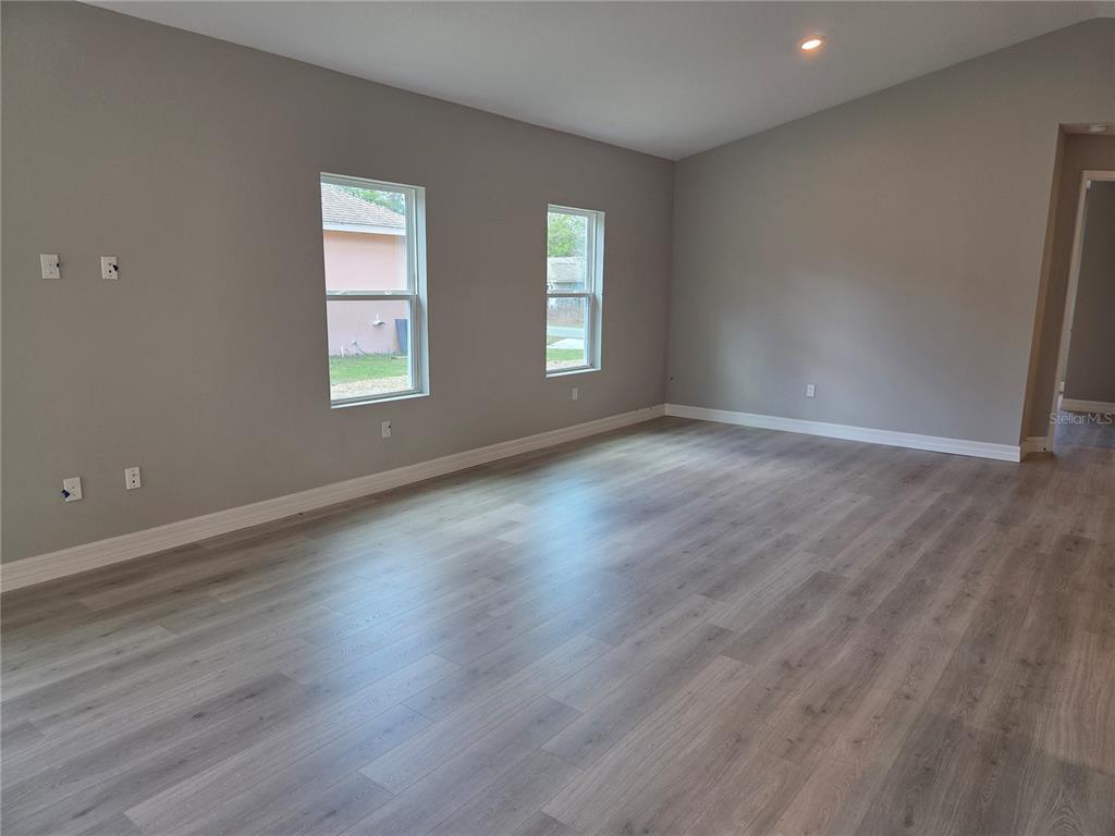 An empty room features gray walls, light wood-look flooring, and two windows — 2992 W HAMLET PLACE, DUNNELLON, FL