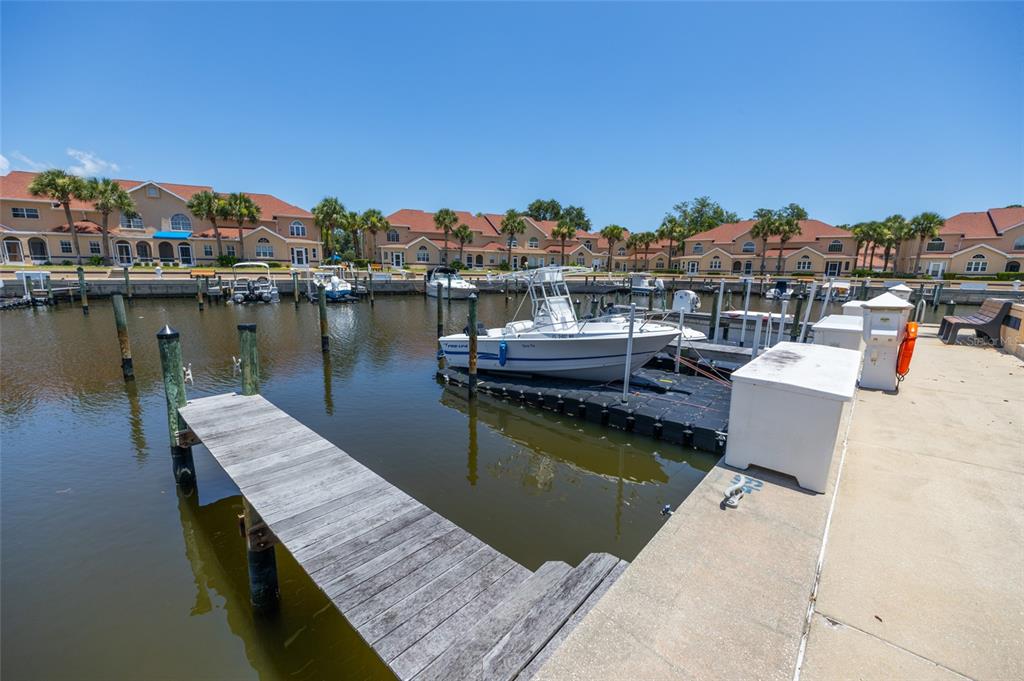 A boat is docked at a pier in front of a waterfront residential complex — 49B MARINA POINT PLACE UNIT SLIP  49B, PALM COAST, FL