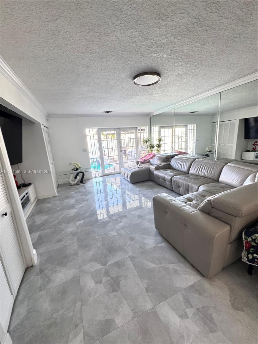 A living room features gray tile flooring, a large sectional sofa, and a mirrored wall — 1314 W 77th St, Hialeah FL 33014, HIALEAH, FL