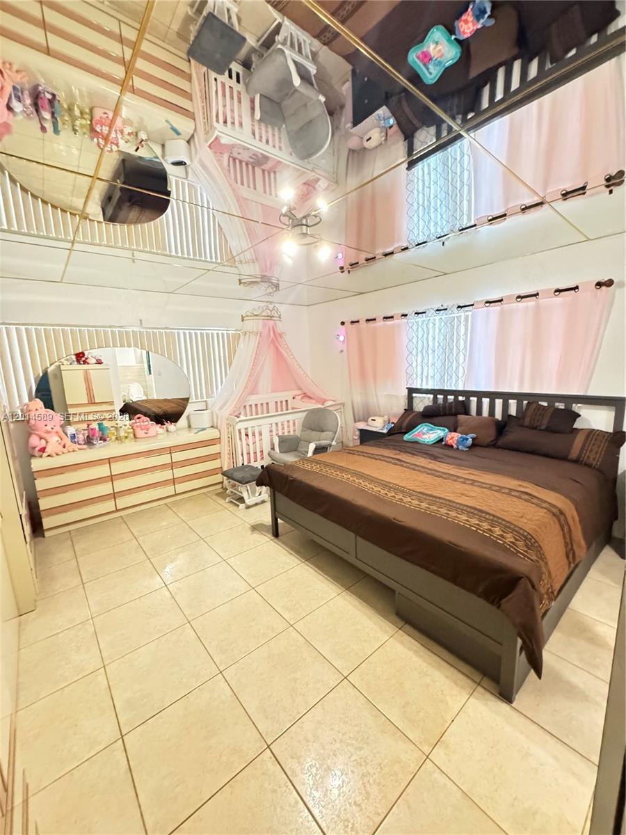 A bedroom features a large bed, a crib with a canopy, and a mirrored ceiling — 1314 W 77th St, Hialeah FL 33014, HIALEAH, FL
