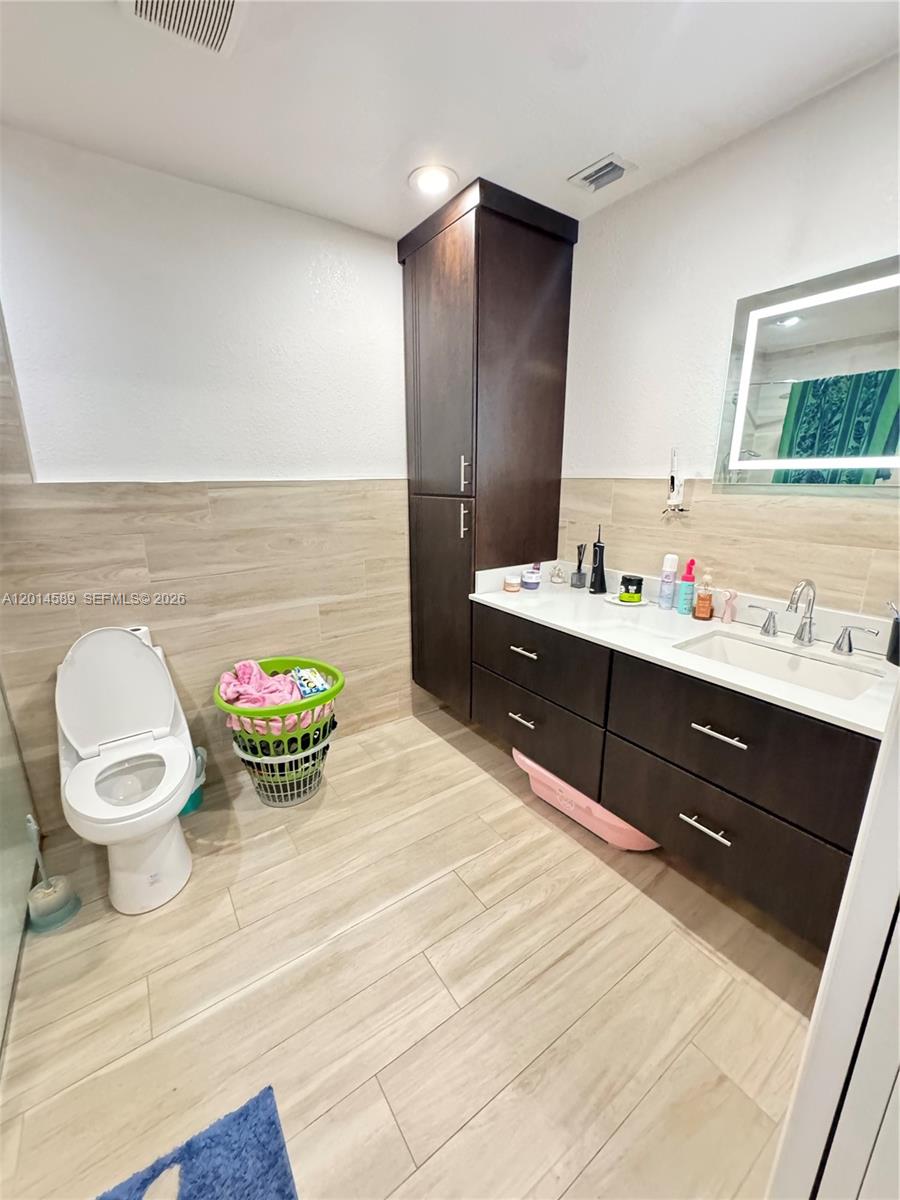 A bathroom features a dark wood vanity, a tall storage cabinet, and light-colored tile flooring — 1314 W 77th St, Hialeah FL 33014, HIALEAH, FL