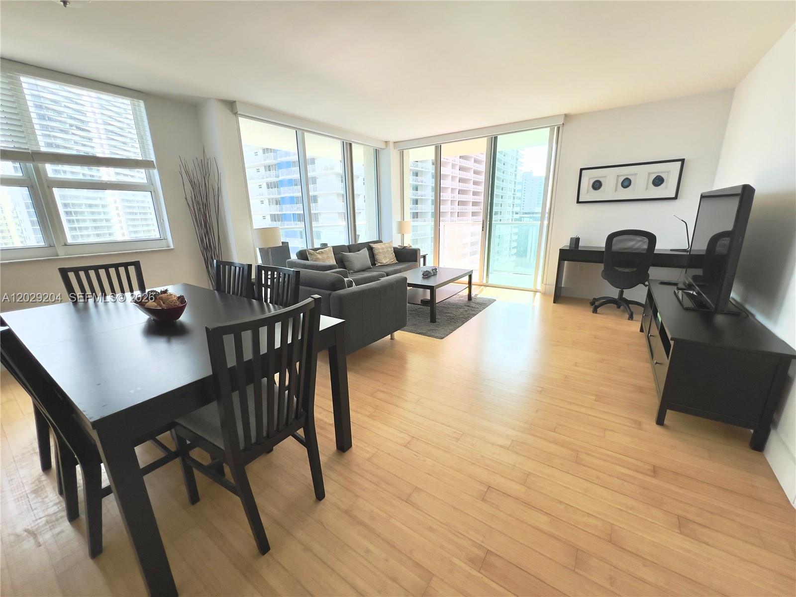 An open-concept living and dining area features light wood flooring and floor-to-ceiling windows — 1155 Brickell Bay Dr # 2701, Miami FL 33131, MIAMI, FL