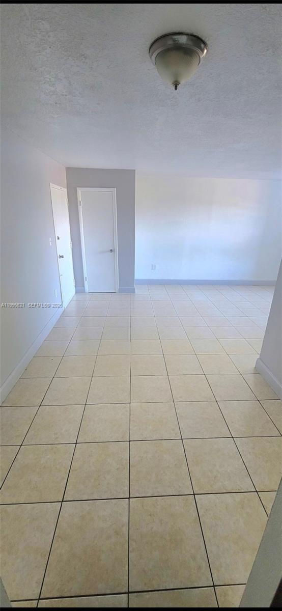 An empty room features light-colored square floor tiles, white walls, and two closed white doors — 1805 W 56th St # 209, Hialeah FL 33012, HIALEAH, FL