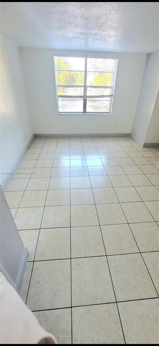 An empty room features white walls, a single window, and light-colored square floor tiles — 1805 W 56th St # 209, Hialeah FL 33012, HIALEAH, FL