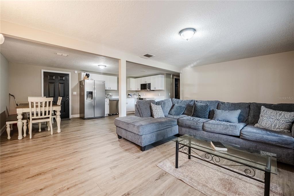 An open-concept living room and kitchen featuring light wood flooring and a gray sectional sofa — 801 N CLERMONT AVENUE, FORT MEADE, FL