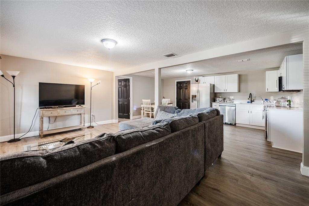 A living room with a gray sectional sofa opens into a kitchen with white cabinets — 801 N CLERMONT AVENUE, FORT MEADE, FL