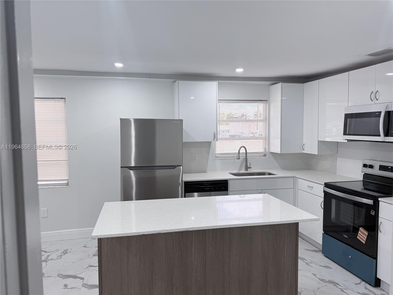 A modern kitchen features white cabinets, stainless steel appliances, a kitchen island, and marble flooring — 6829 SW 25th St, Miami FL 33155, MIAMI, FL