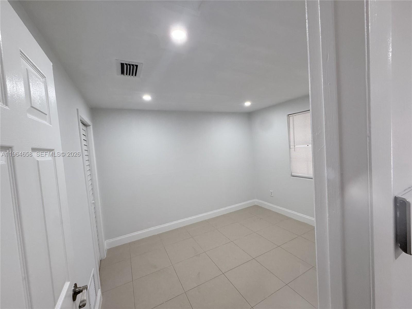 A small, empty room features light gray walls, recessed ceiling lights, and beige tile flooring — 6829 SW 25th St, Miami FL 33155, MIAMI, FL
