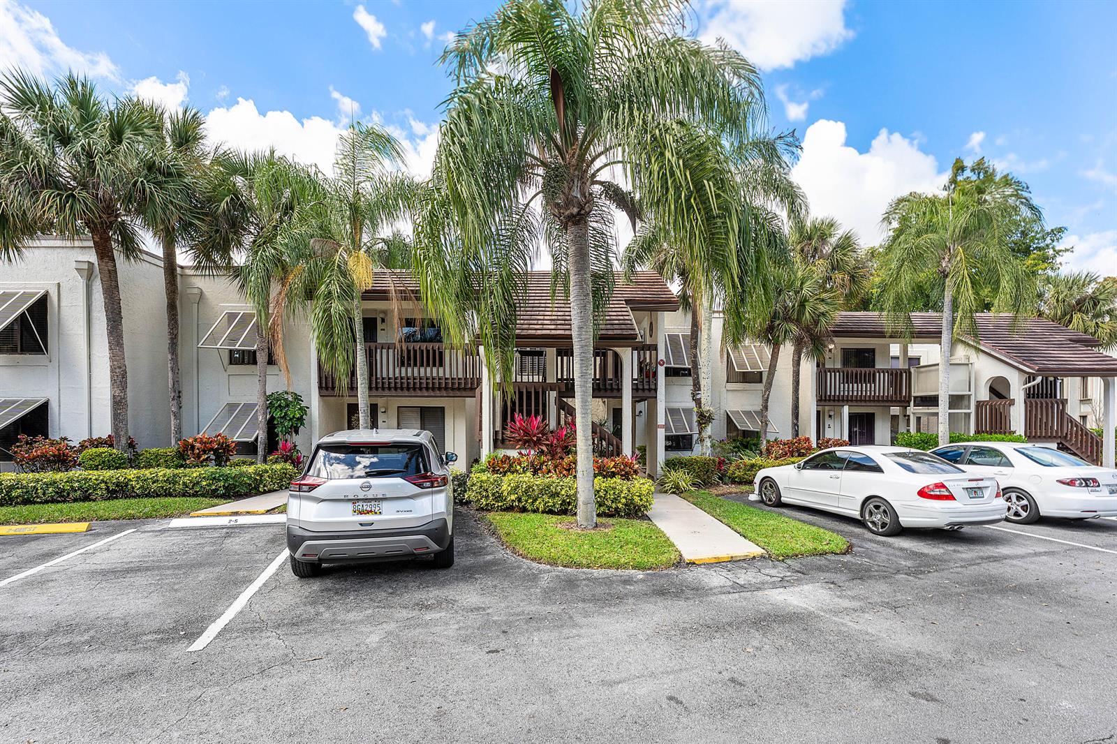 A two-story apartment complex features a parking lot, palm trees, and balconies — 10155 Mangrove Drive # 204, Boynton Beach FL 33437, BOYNTON BEACH, FL