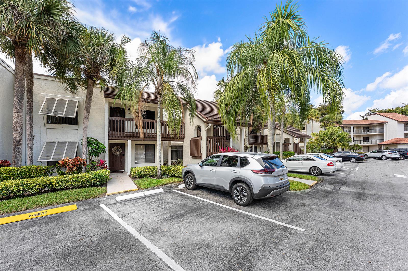 A two-story apartment building with palm trees and parked cars in the foreground — 10155 Mangrove Drive # 204, Boynton Beach FL 33437, BOYNTON BEACH, FL