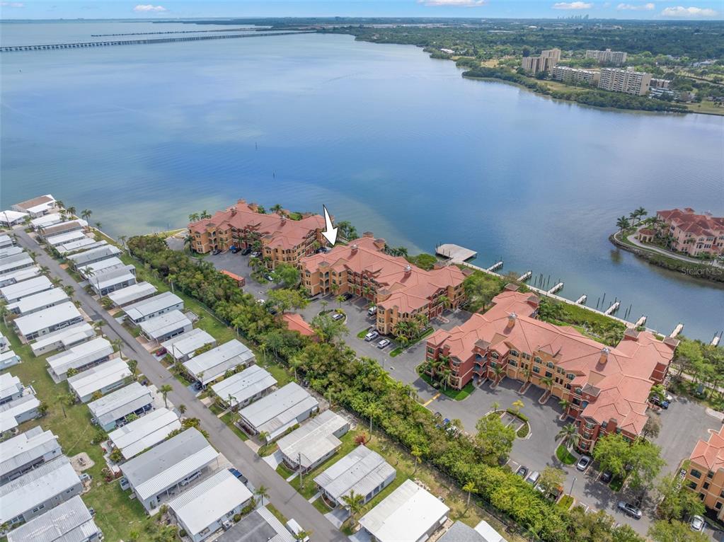 An aerial view shows waterfront apartment buildings next to a row of mobile homes — 2765 VIA CIPRIANI UNIT 1232A, CLEARWATER, FL