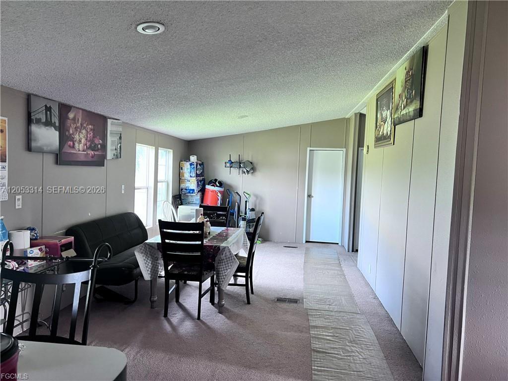 This dining area features a table with chairs, a black sofa, and beige walls — 3704 Dustin, La Belle FL 33935, LA BELLE, FL