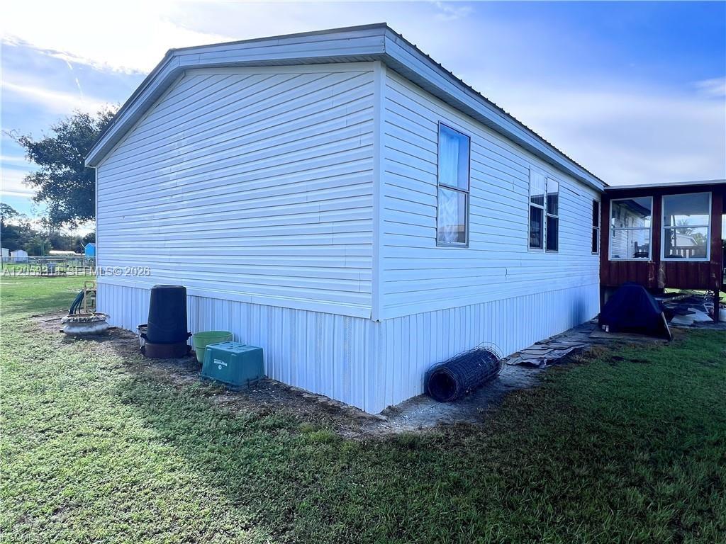 The exterior of a white mobile home features vertical skirting and a small attached porch — 3704 Dustin, La Belle FL 33935, LA BELLE, FL